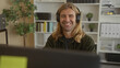 © Krakenimages.com - Man with black headphones looking at computer screen in office building; concentration dedication persistence.