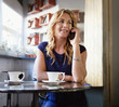 © peopleimages.com - Phone call, listening and relax with woman in cafe for communication, break and contact. Connection, restaurant customer and tea cup with person and tech in coffee shop for conversation and drink