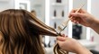 © antuanetto - Hairstylist applying balayage highlights to female client's long brown hair in a salon for beauty transformation concept and professional hair care
