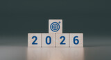 Wooden cubes with the text 2026, an arrow, and a target. Concept of business goals, strategy, and financial planning for the new year. 3D rendering.