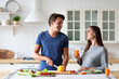 © BestForYou - Couple in the kitchen preparing a dish from healthy vegetables, chatting happily, balanced nutrition.