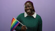 © Krakenimages.com - Woman smiling holding rainbow flag against isolated purple background celebrating lgbtq pride with vibrant expression and joyful demeanor.