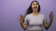 © Krakenimages.com - Young hispanic woman laughing with open mouth and hands raised, hair blown and lilac top visible in purple studio; joy celebration energy.