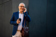 © Jelena - Mature businessman smiling talking on smartphone drinking coffee