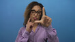 © Krakenimages.com - Hispanic transgender woman wearing purple blouse forms l shape gesture with raised hand in blue studio; mockery.