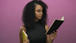 © Krakenimages.com - Young woman with glasses reading a book against a vibrant pink background, focused and inquisitive, showcasing a modern intellectual vibe with a simple, isolated setting.