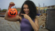 © Krakenimages.com - Woman holding pumpkin basket at construction site, smiling outdoors, showcasing festive spirit in work environment, blending halloween fun with outdoor setting in casual style.