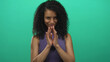 © Krakenimages.com - Young woman making a mischievous gesture against an isolated bright green background, emphasizing elements of intrigue and emotion through her expressive eyes and subtle smile.