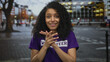 © Krakenimages.com - Young woman wearing volunteer shirt smiles on a city street during daytime showcasing involvement and community.