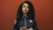 © Krakenimages.com - Woman police officer writing notes on a notepad in a bright red studio setting with serious expression; duty.