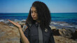 © Krakenimages.com - Young hispanic policewoman in uniform standing confidently by the seaside, showcasing authority and professionalism against a serene beach backdrop.