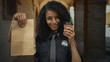 © Krakenimages.com - Woman officer holding coffee cup and paper bag, smiling outdoors in old town street, wearing uniform.