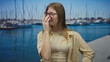 © Krakenimages.com - Blonde woman wearing glasses pinches nose beside boats on sunlit street pier over blue water; disgust.