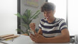 © Krakenimages.com - Teenage boy holds smartphone and makes a fist pump at a study desk inside a building; joy achievement success.