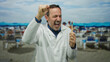 © Krakenimages.com - Middle-aged man in white coat celebrates holding toothbrush on sunny seaside with beach umbrellas.