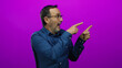 © Krakenimages.com - Mature man with glasses enthusiastically pointing on a vibrant pink background wearing a blue shirt.