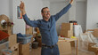 © Krakenimages.com - Man celebrating in new home surrounded by cardboard boxes and unpacked items in a modern living room indicates a successful moving day.