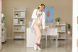 © Pixel-Shot - Young African-American female doctor in headphones dancing and singing in clinic