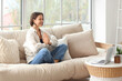© Pixel-Shot - Beautiful young woman with laptop meditating on sofa at home