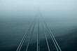 © MDSHAHINUL - Parallel lines disappearing into a dense, atmospheric fog, creating a mysterious and minimalist scene