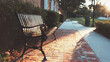 © valeo5 - Vintage-Filtered Close-Up of an Empty Black Cast Iron Park Bench Resting on a Brick Sidewalk as the Warm Sunset Light Casts Long Shadows