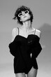 © SHOTPRIME STUDIO - Stylish woman in black dress wearing white sunglasses, posing confidently with short hair in a black and white studio setting.