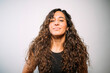 © karrastock - Young adult woman smirking with long curly hair