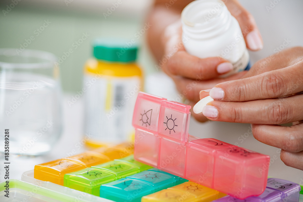 Medication adherence. Preparing a pill box to manage her medication ...