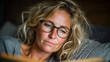 © vetre - Thoughtful Reading. A person with glasses in cozy attire thoughtfully reads indoors.