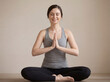 © Artem - Woman practices yoga in a simple indoor space while sitting in a cross-legged pose and smiling