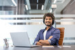 © Tetiana - Portrait of a young smiling Muslim man in a shirt and headphones sitting at a desk in the office, confidently crossing his arms over his chest and looking at the camera