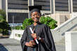 © Wavebreak Media - African American woman in cap and gown standing on university plaza holding diploma, smartphone