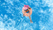 © Iuliia Sokolovska - Aerial drone view of beautiful woman in hat relaxing in swimming pool, young girl in bikini swims on inflatable ring donut and has fun in blue pool water, tropical vacation on holiday resort