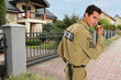 © New Africa - Security guard using radio near house outdoors. Private property protection