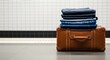 © antuanetto - Folded pants and jeans neatly stacked on a vintage leather suitcase for journey preparation concept, ready for a 'No Trousers Ride' adventure