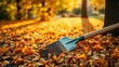 © xiaolei - woodsy. An autumn garden scene with a rake resting on golden leaves, bathed in warm sunlight filtering through trees. representing seasonal cycles and harvest abundance.