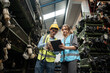 © chachamp - Portrait Caucasian woman and Asia man engineer or mechanic use tablet computer checking auto part or car part at car part warehouse