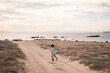 © Cavan Images - A young boy runs down a sand road at the beach