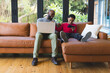 © Wavebreak Media - African American father and son browsing laptop and smartphone on sofa beneath living room windows