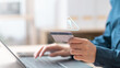 © sornthanashatr - Person holding credit card with virtual warning icon, representing fraud alerts and digital security risks. Suspicious charge fraud alert. symbolizing fraud alerts and secure transaction monitoring.