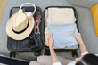 © Pormezz - person checking list of stuff to prepare suitcase before travel