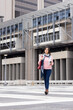 © Wavebreak Media - Hispanic senior woman crossing striped crosswalk at office carrying to-go coffee cup, red tote bag