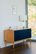 © Wavebreak Media - Navy blue ribbed sideboard standing in living area holding glass terrarium, smart speaker, lamp