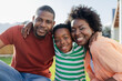 © Wavebreak Media - African American family sitting and smiling on front yard grass near wooden fence with house facade