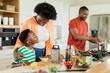 © Wavebreak Media - African American family stirring pot and grating cheese at kitchen island with cherry tomatoes