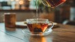 © Proshanto Mondol - Tea Pouring: Close-up shot of a glass cup filling with tea from glass pitcher on a wooden table, depicting the process of brewing tea, symbolizing warmth and comfort.