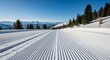 © antuanetto - Empty groomed ski trail stretching through a pristine snowy mountain landscape under clear blue sky for winter sports and serene nature concept