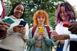 © Daniel - Group of diverse students using smartphones outdoors, browsing internet and social media