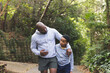 © Wavebreak Media - African American father and son walking on paved park trail wearing gray hoodies beside stone wall