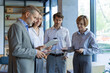 © ty - Successful businesspeople working in a coworking space working with digital tablet discussing strategy and business plan in modern office.